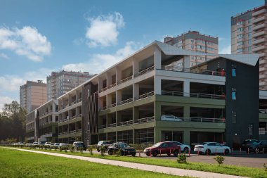 Konut kompleksinde büyük, modern, çok katlı bir park yeri. Yerleşim yerlerinin arkaplanlarına ve bulutlu güzel gökyüzüne karşı.