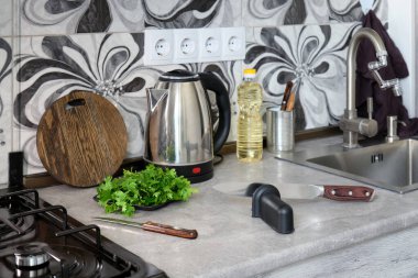 Bıçakları bilemek için özel bir alet ve masada büyük bir mutfak bıçağı. Ahşap kesim tahtası, gaz sobası ve mutfak aletlerinin arka planında..