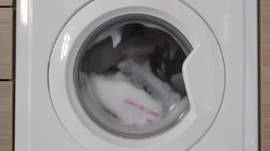 Yakın çekim, spor ayakkabılarını çamaşır torbasında, çamaşır makinesinde yakın davulla yıka.. 