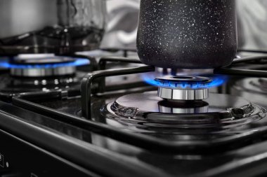 Ev mutfağındaki ocağın üzerinde mavi bir alev olan ocağı kapat. Evde yemek pişirmek..