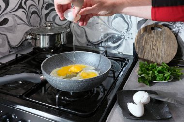 Bir adam, gaz ocağındaki mutfağında çırpılmış yumurta pişiriyor..