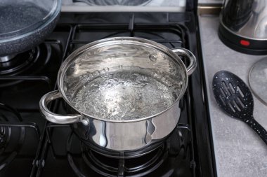 Gaz sobasının üzerinde kaynar su bulunan metal bir tencereye yakın çekim. Evde yemek pişirmek..
