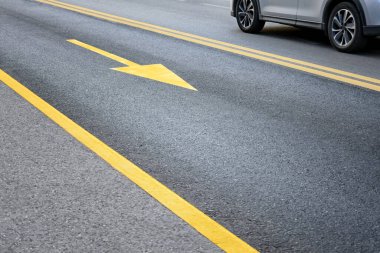 Sarı yol tabelası ve yolda gidiş yönünü gösteren bir ok. Yol güvenliği kavramı.