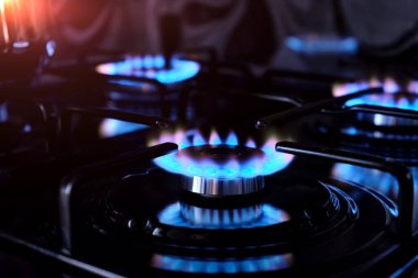 Gaz birçok mutfak sobasının ocağında yanar. Mutfak ocakları karanlıkta yanıyor..