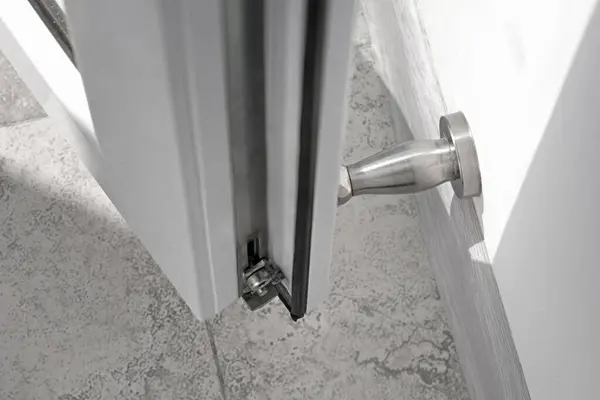 stock image Top view on a stainless steel wall mounted doorstop and metal-plastic door in a renovated apartment to prevent a door from opening too widely. Details in the interior.