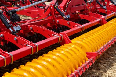 Close-up of a large modern plow yellow color or disc harrow for cultivating the land. New model of agricultural equipment. Selective focus. clipart