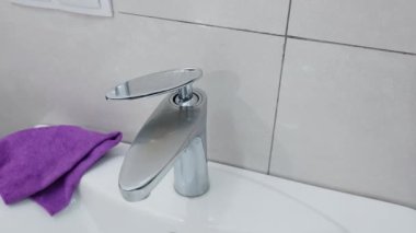 Bir adam banyoda eski bir top vanasını yağlamak için sprey ve yenileme sıvısı kullanır..