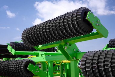 Close-up of a rotary harrow green color for processing an agricultural field. Against the background of the blue sky and clouds. Conceptual image. clipart