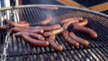 Izgarada ızgarada ızgara yapan büyük sığır eti sosislerini kapatın. Büyük bir grup insan için lezzetli yiyecekler..