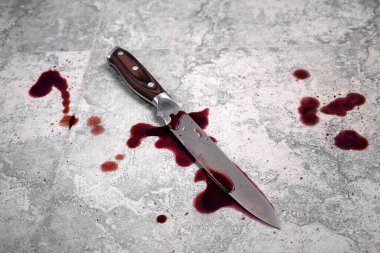 Üst manzara, yerde kanlı bıçaklı bir suç mahalli. Evde şiddet, evlilik ya da birlikte yaşama. Seçici odak.