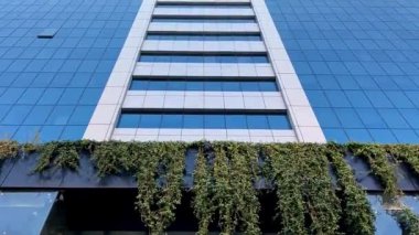 Bulutlu mavi gökyüzüne karşı çok güzel bir cam ofis binası. Kamera hareketiyle aşağıdan görüntüle.