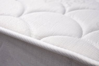 Yeni beyaz bir yatak yakın plan. Yatak kenarı. Seçici odak.