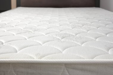 Küçük bir dairede ya da evde gri yataktaki yeni beyaz yatağı kapat. Yatak kenarı. Seçici odak.