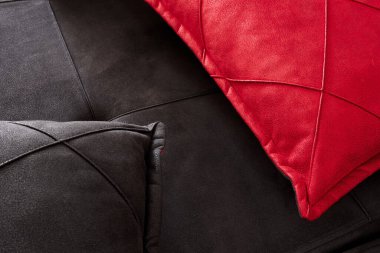 İki güzel siyah ve kırmızı yastıkla suni deriden yapılmış bir kanepenin üst görüntüsü. Seçici odak.