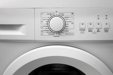 Modern bir çamaşır makinesinin kontrol panelinin önünde beyaz bir renk. Yıkama kipini seçmek için çember seçici. 