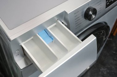 Çamaşır odasında çamaşır makinesinde bulaşık yıkamak için açık konteynır ya da jel. Seçici odak.