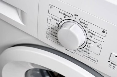 Modern bir çamaşır makinesinin kontrol paneline yakın plan beyaz renk. Çamaşır modunu seçmek için çember seçici. Seçici odak.