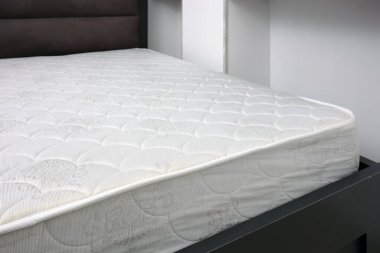 Gri yataklı, kapalı, üst manzaralı yeni beyaz yatak. Yatak kenarı. Seçici odak.