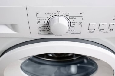 Kontrol panelinin üst görüntüsü ve modern çamaşır makinesi gri renginin davul yarışmacısı. Çamaşır modunu seçmek için çember seçici. Seçici odak.