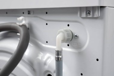 Ev ya da apartmandaki bir çamaşır makinesine soğuk su bağlamak için hortum. Arka tarafta çamaşır makinesi var..