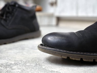 Siyah deri yırtık eski bir botu yakın plan çek. Yoksulluk kavramları.