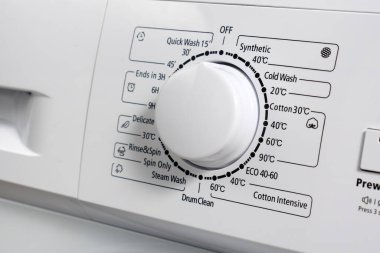 Modern bir çamaşır makinesinin kontrol paneline yakın plan gri renk. Çamaşır modunu seçmek için çember seçici. Seçici odak.