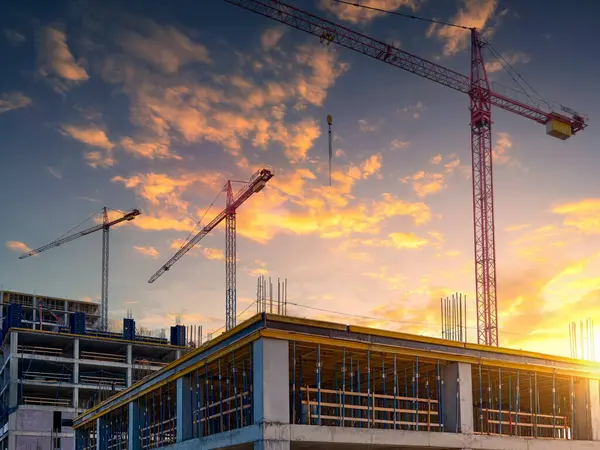Yeni bir yerleşim kompleksinin inşaatı. Güzel bir günbatımı gökyüzünün arka planına karşı gökdelenler..
