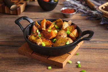 Soğanlı patates ve ahşap bir masada, siyah dökme demir bir tavada dereotu pişirdim. Evde yemek pişirmek..