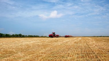 Yabani otlarla işlenmemiş tarla. Tarlada sabanla büyük bir traktör işi. Hasattan sonra ekime başlayın. Tarımsal ekipman işi.