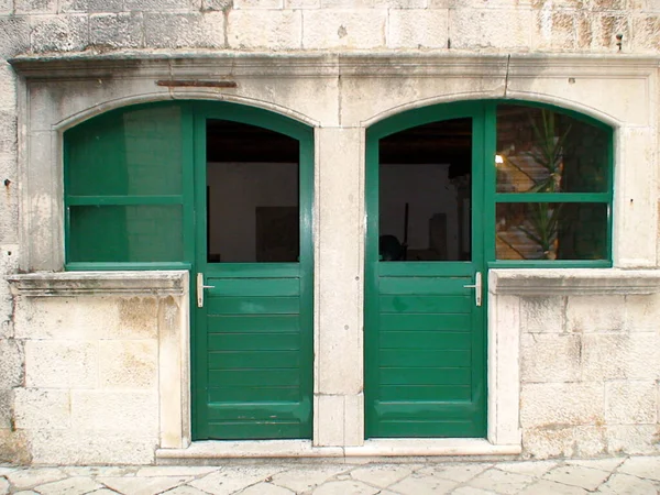 Old and solid double door and double window in solid wood of a house on the island of Korcula on the Adriatic Sea in Croatia in the region of Dubrovnik, nicknamed the pearl of the adriatic