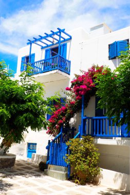 Beyaz çiçekli ve mavi kapılı güzel bir ev. Mykonos 'ta, Ege Denizi' nin göbeğinde, Cyclades Takımadaları 'nın ünlü adası.