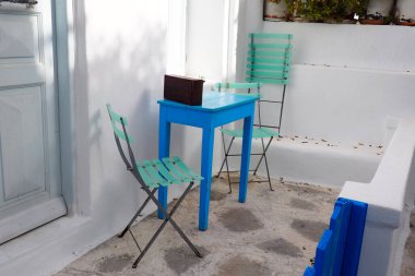 Yunan Cyclades adası Mykonos 'un cazibelerinden biri dar kaldırımlı sokakların beyaz evlerinin zemin katındaki renkli masaları ve sandalyeleriyle küçük teraslardır.