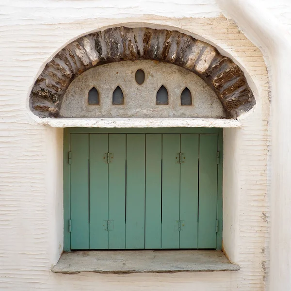 the solid old doors and windows in painted wood are one of the charms of the Cyclades, in the heart of the Aegean Sea, here in Tinos in the famous white village of the marble craftsmen of Pyrgos