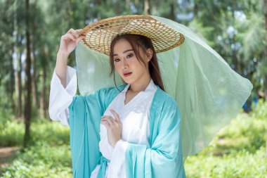 Young beautiful Asian woman dressed in ancient Chinese warrior style with ancient fan. cute girl in green dress