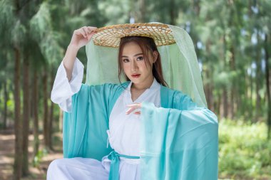 Young beautiful Asian woman dressed in ancient Chinese warrior style with ancient fan. cute girl in green dress