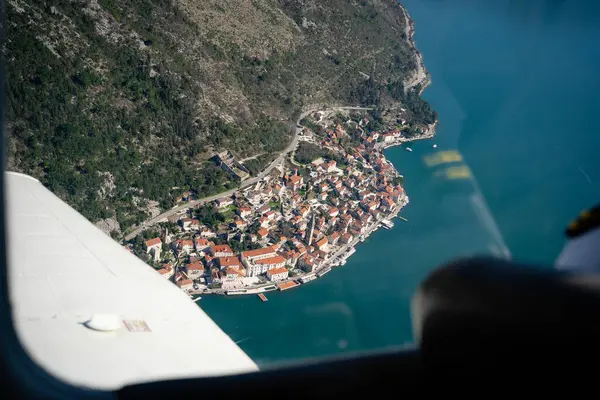 Coastal Town ve Airplane Wing 'in hava görüntüsü. Dağlar ve deniz arasında kurulmuş, bir uçak kanadından görülen tuhaf bir sahil kasabasının yüksek kaliteli fotoğraf perspektifi.. 