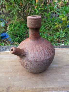 Kendi ya da sürahi, çamurdan yapılmış çaydanlık şeklinde su depolamak için kullanılan bir kap. Arka planı bulanık olan ahşap bir kâsenin yakın plan çekimi.