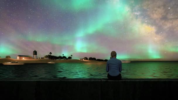 Зеленая Aurora Borealis Над Женщиной Сидящей Заднем Виде Бетонном Сиденье — стоковое видео