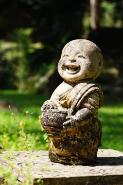 Çocuk keşiş mutlu gülen surat Buda, Wat Pha Lat, Doi Suthep, Chiangmai tapınağı, Tayland 'da yeşil manzaralı eski taş heykel süslemesi 