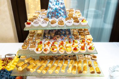 Çikolata. Piramit şeklinde çok aşamalı platformda çeşitli parlak tatlılar.