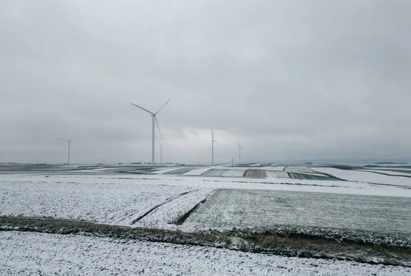 Snow in winter on a rural field with a wind farm