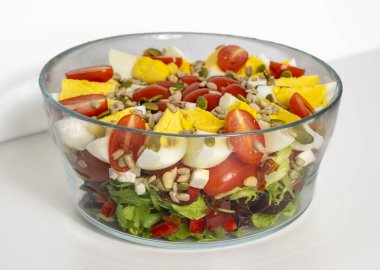 Salad with quartered egg, tomato, lettuce, and grains in a bowl