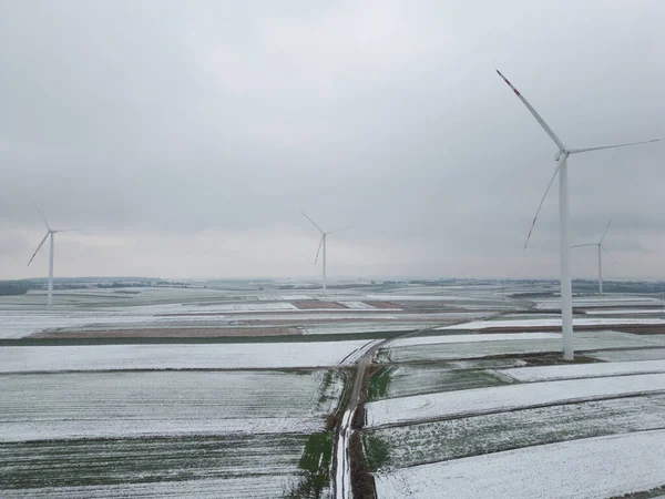 Field troga among windmills on the first snowy day. Top view, sky background in fog