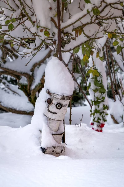A wooden statue - a smiling man in a big snow among trees and bushes