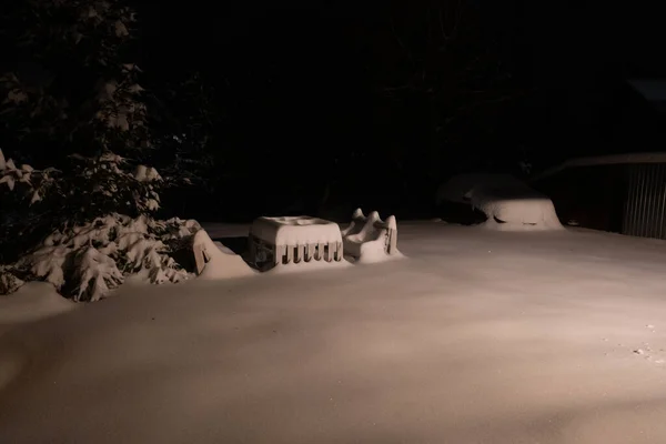 Snowy bench made of pallets at dark night