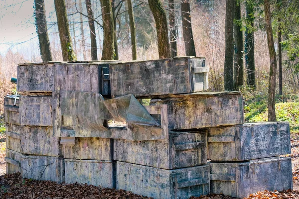 Wall made of chests and Paintball trunks to hide, fortification among the trees. Arena for shooting colored paint balls.