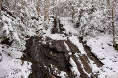 Snow covered river and waterfall with mountains in winter