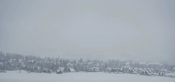 Panorama of snow covered houses in the mountains in the fog in winter