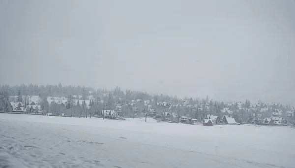 Panorama of snow covered houses in the mountains in the fog in winter