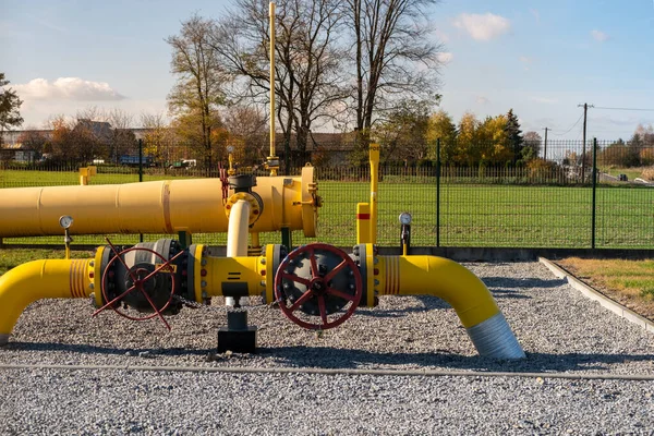 Big gas pipe - natural gas transport system. Transmission infrastructure coming from the ground, yellow pipes with a safety valve